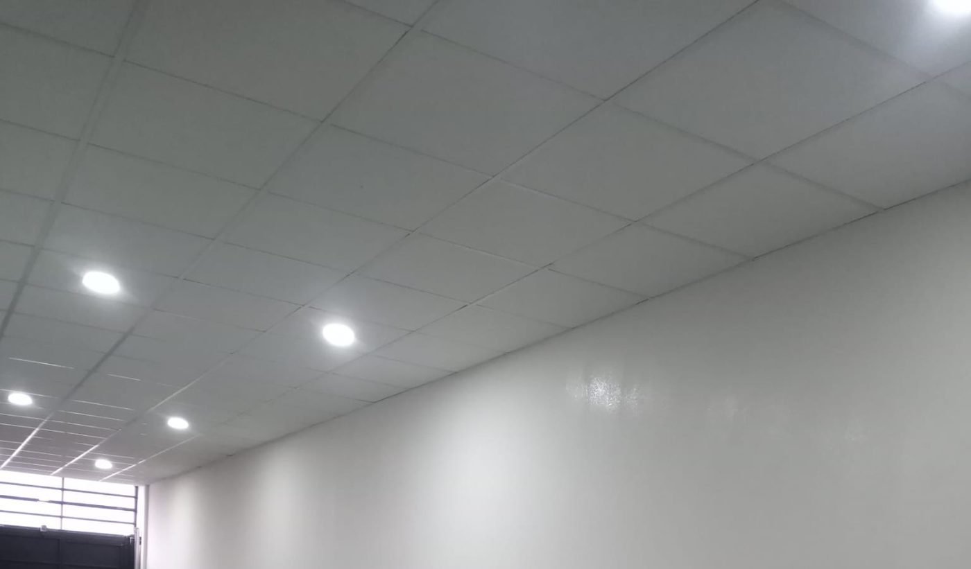 Pasillo recién pintado de blanco con techo técnico, reforma realizada por Obrax