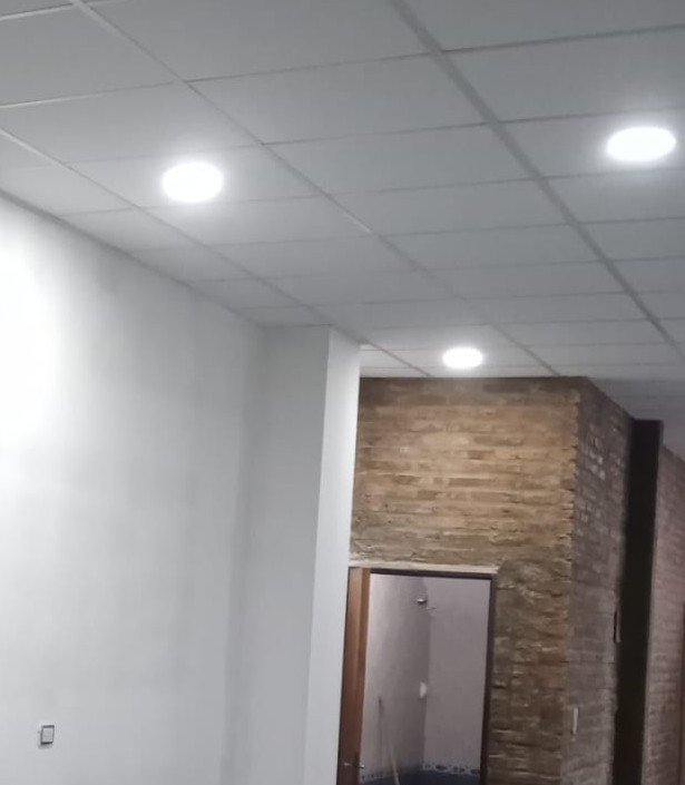 Pasillo con muro de piedra vista y techo técnico, reforma realizada por Obrax